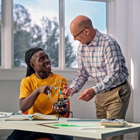 A high school student is learning science from a teacher in a one-one-one setting.